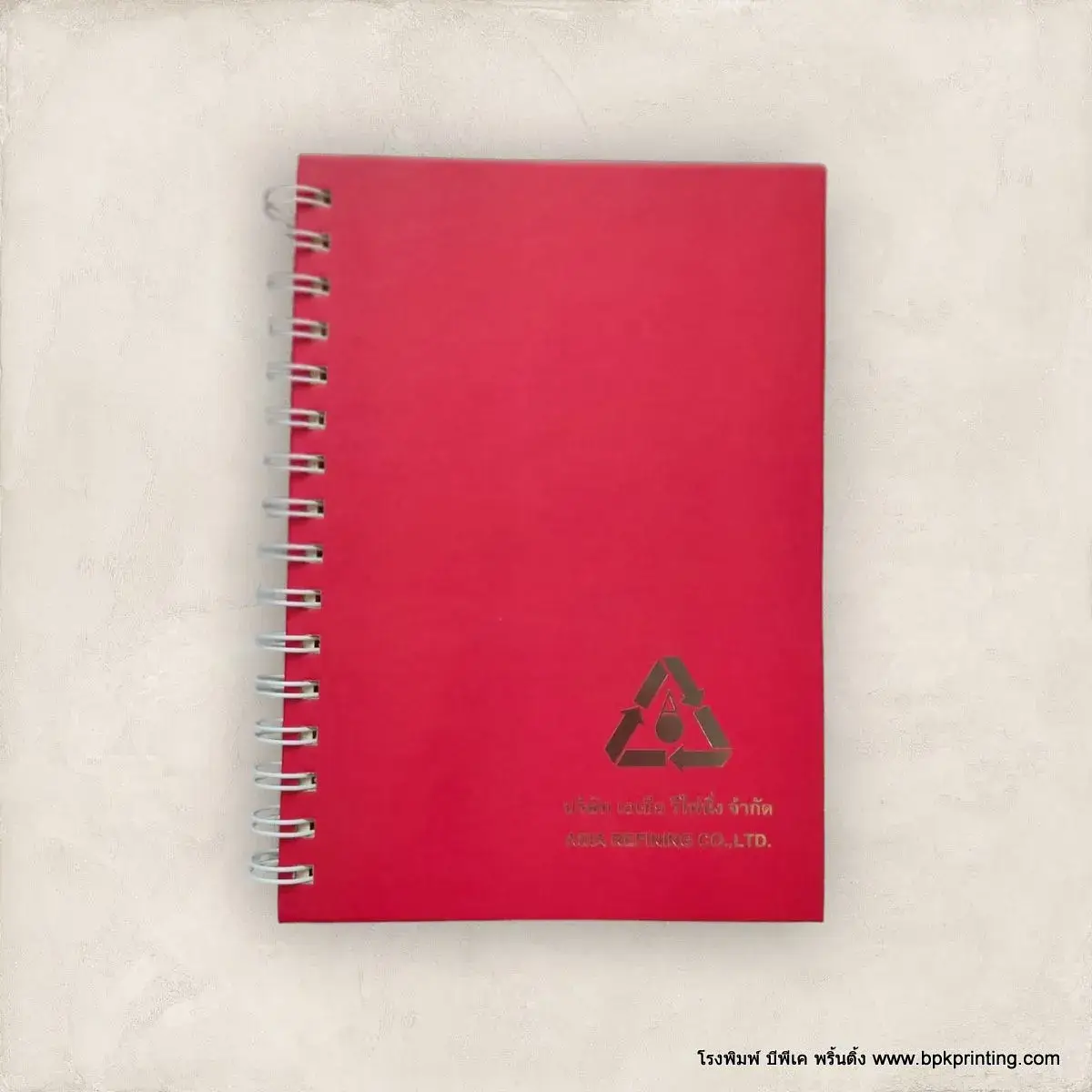 สมุดโน้ตปกแข็งสีแดงเข้มเข้าเล่มแบบห่วงโลหะ พร้อมปั๊มโลโก้บริษัท Asia Refining Co., Ltd. ด้วยฟอยล์เงินเงา เพิ่มความหรูหราและมืออาชีพ เหมาะสำหรับแจกในงานสัมมนา องค์กร หรือเป็นของขวัญลูกค้า พิมพ์และผลิตโดยโรงพิมพ์ BPK Printing คุณภาพระดับพรีเมียม