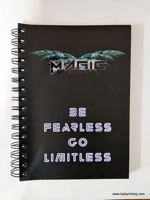 สมุดโน้ตปกสีดำเข้มดีไซน์ล้ำสมัย พิมพ์โลโก้ MAGIC พร้อมข้อความ “BE FEARLESS GO LIMITLESS” ด้วยฟอนต์แนวนีออนสุดโดดเด่น เย็บเข้าเล่มแบบสันห่วงสีดำทนทาน โรงพิมพ์ BPK Printing รับผลิตสมุดโน้ตองค์กร ปกคัสตอมคุณภาพสูง เหมาะสำหรับแจกในงานสัมมนา อีเวนต์ หรือใช้สร้างแบรนด์ในองค์กร