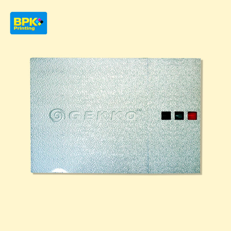 หน้าปกแคตตาล็อก GEKKO พิมพ์โดยบีพีเค พริ้นติ้ง ดีไซน์พื้นผิวลายหยาบพร้อมโลโก้นูนและปุ่มสีแดง เขียว ดำ ใช้สื่อถึงระบบควบคุมหรืออุปกรณ์อุตสาหกรรม