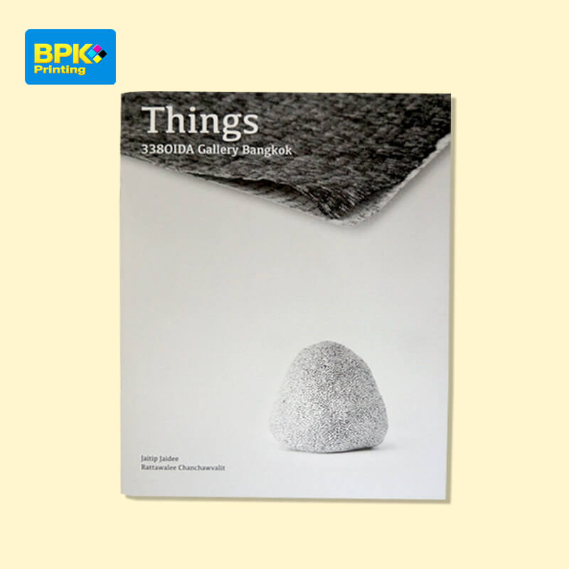 หน้าปกหนังสือ Things จัดแสดงโดย 338OIDA Gallery Bangkok พิมพ์โดยบีพีเค พริ้นติ้ง ดีไซน์มินิมอลด้วยพื้นหลังสีเทา มีวัตถุเนื้อผิวหยาบวางอยู่กลางหน้า พร้อมชื่อศิลปิน Jaitip Jaidee และ Rattawalee Chanchawalit