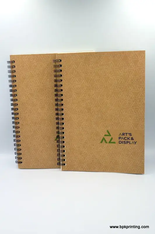 สมุดโน้ตปกคราฟท์เย็บห่วงโลหะ พิมพ์โลโก้ ART’S PACK & DISPLAY พร้อมลวดลายสามเหลี่ยมลายเส้นสุดคลาสสิก เหมาะสำหรับองค์กรที่ต้องการภาพลักษณ์เป็นมิตรกับสิ่งแวดล้อม โรงพิมพ์ BPK Printing รับผลิตสมุดโน้ตปกคราฟท์คุณภาพสูง พร้อมงานพิมพ์โลโก้ตามแบบ ช่วยสร้างแบรนด์อย่างยั่งยืน