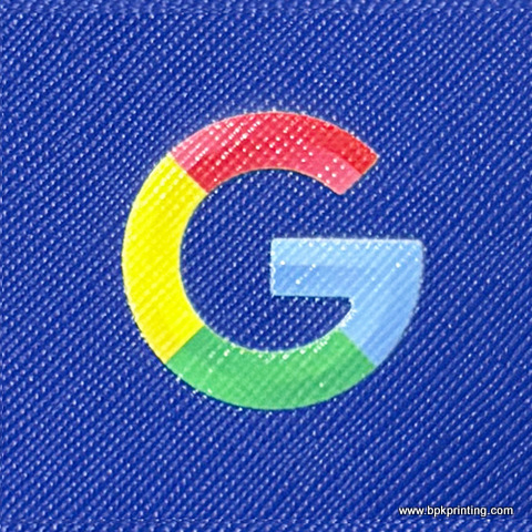  โลโก้ Google สีสันสดใสพิมพ์ลงบนพื้นผิวหนังเทียมสีน้ำเงินเข้มที่มีลายเส้นเฉียง พร้อมระบุเว็บไซต์ www.bpkprinting.com ที่มุมล่างขวาของภาพ